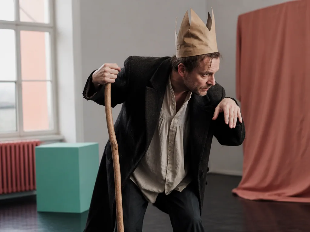 Ubu Roi, personnage grotesque à couronne et sceptre, sur scène de théâtre, criant merdre